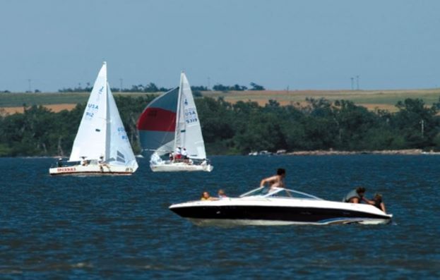 Two sail boats and one smaller boat with passengers swimming in the lake