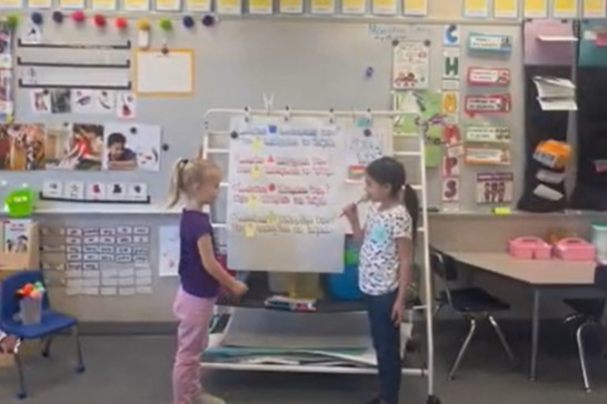 Two students stand in front of the Dual Immersion Class.; one holds a microphone.