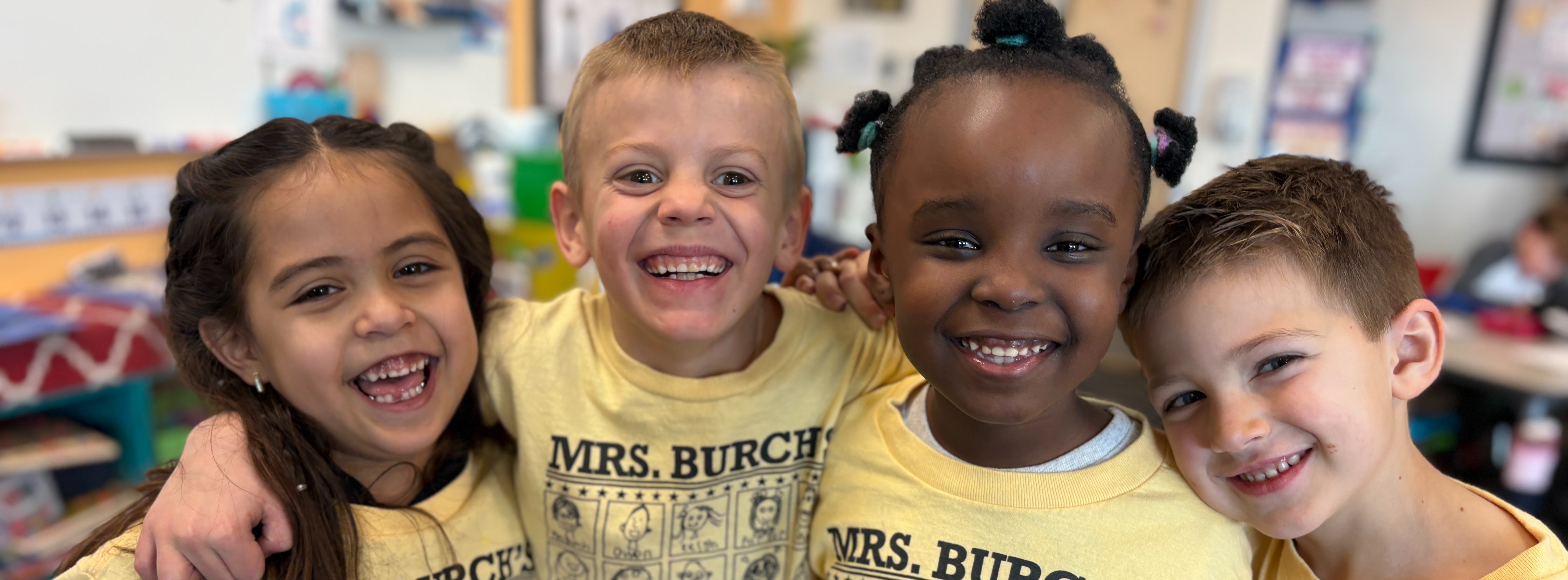 Elementary School students smile in matching shirts.