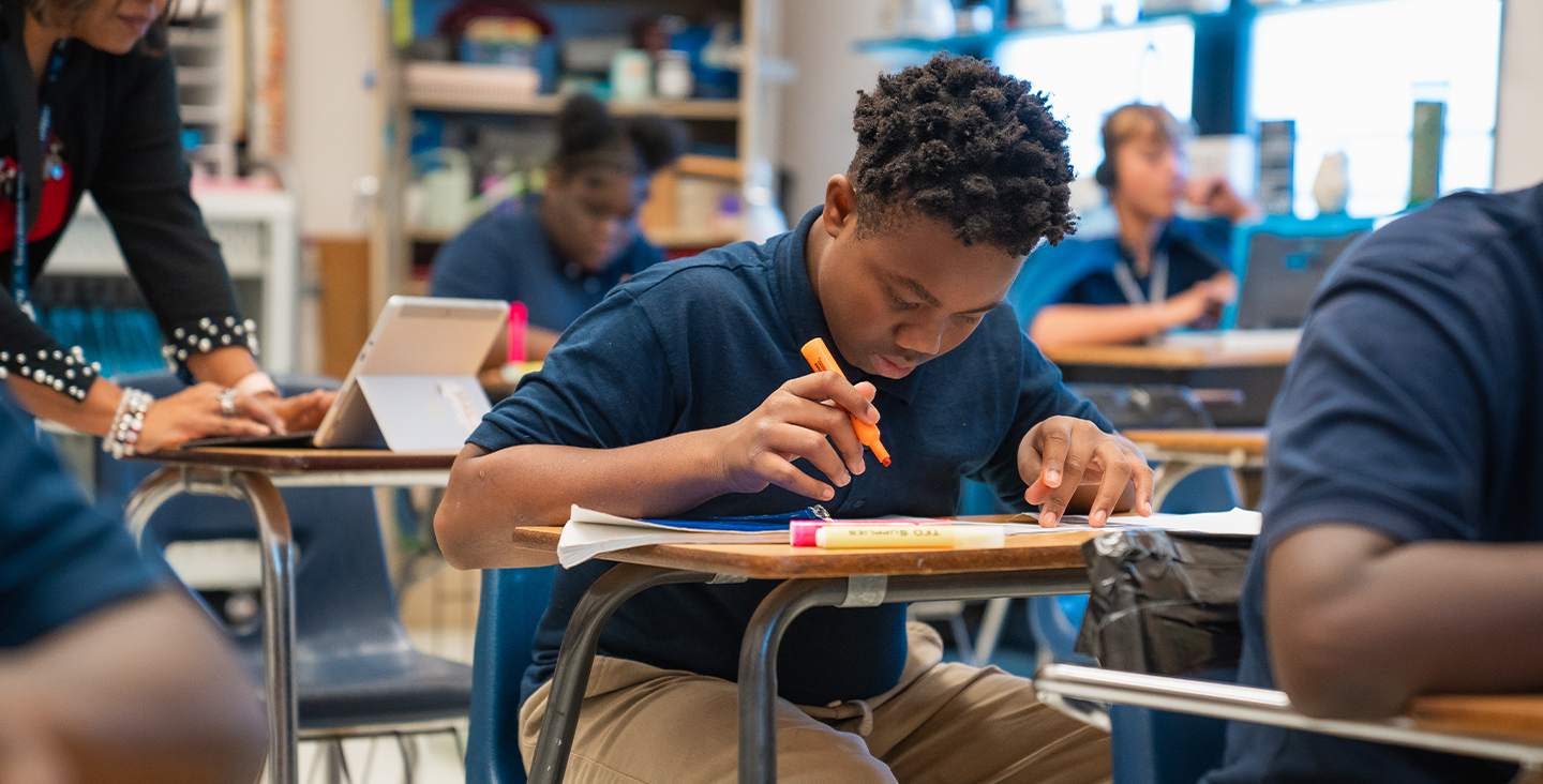 student at a desk highlighting assignments