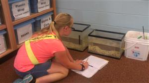 girl with two terrariums in front and taking notes in notebook