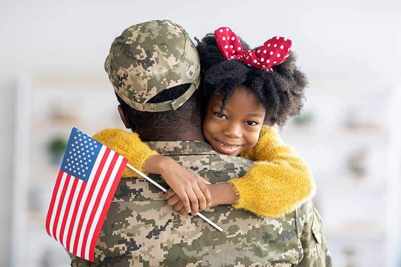 Military with girl in arms smiling to camera