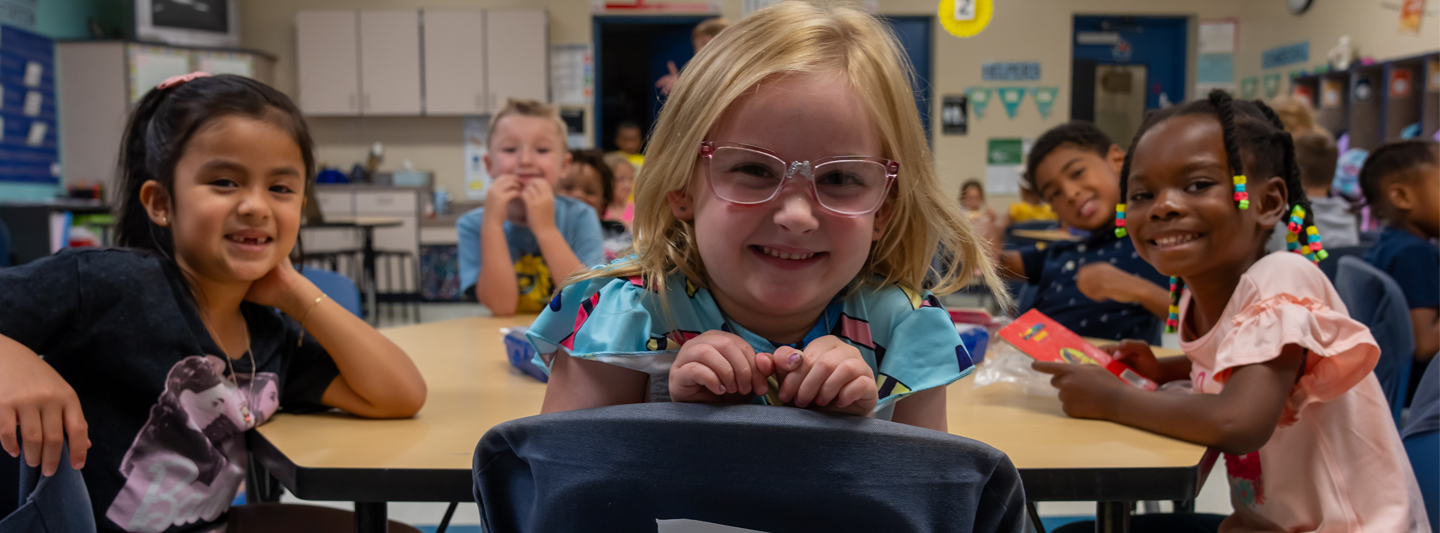 students at a table, turned around in their seats smiling