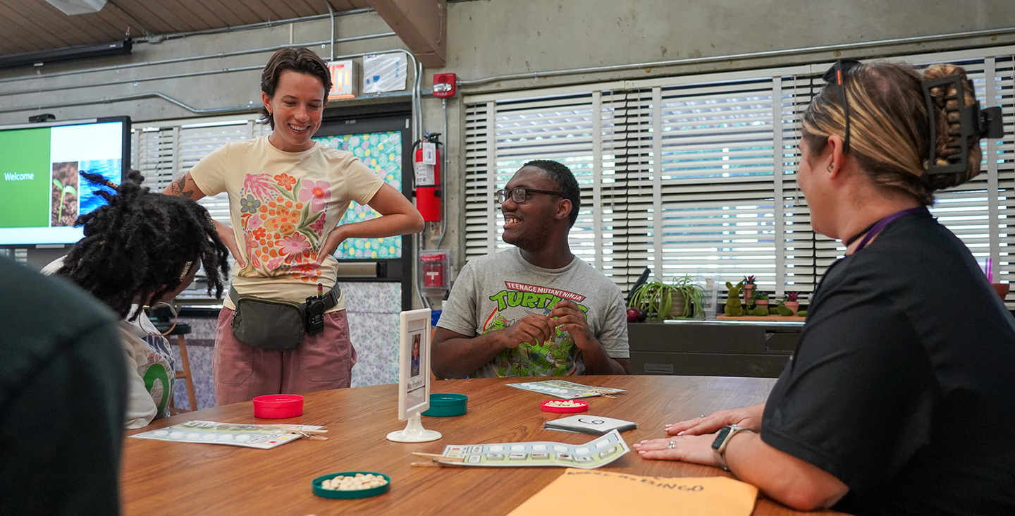 students laughing with their teacher at a table working on math