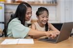 mom sitting with her daughter in front the computer