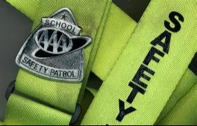 Bright yellow strap displays "Safety" text and a silver badge reading "School Safety Patrol" with an outline of a hat.