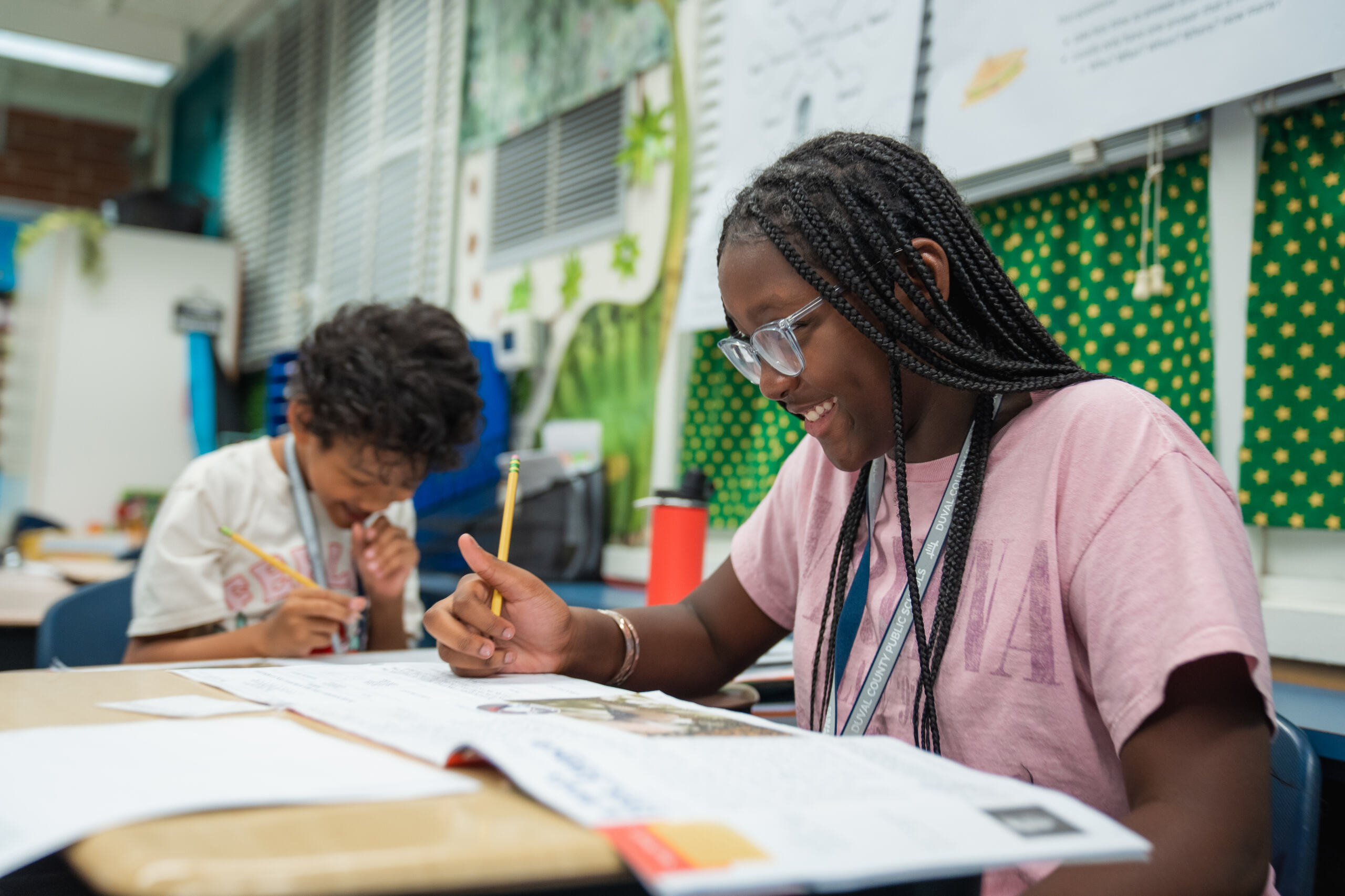 A student smiling and working on a class assignment