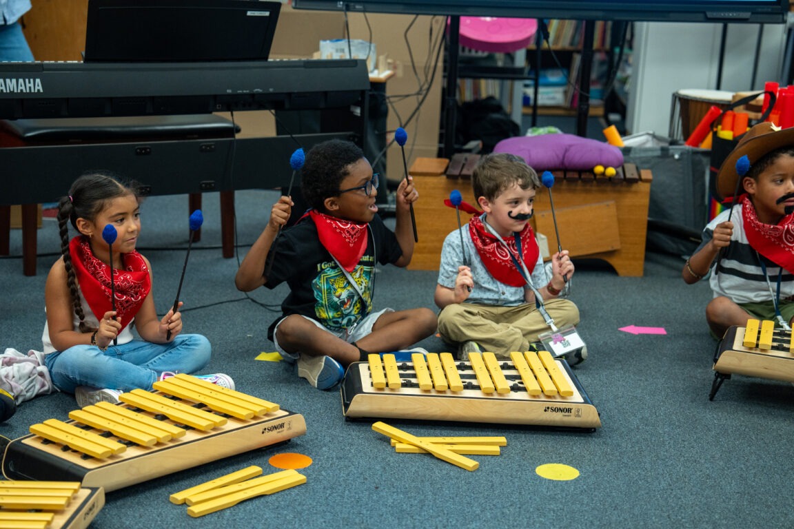 Studens sitting down in a circle playing an instrument