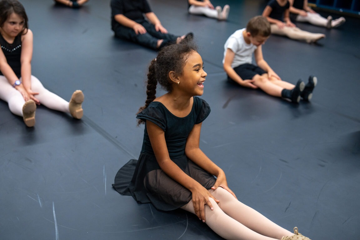 A student sitting and smiling in dance class