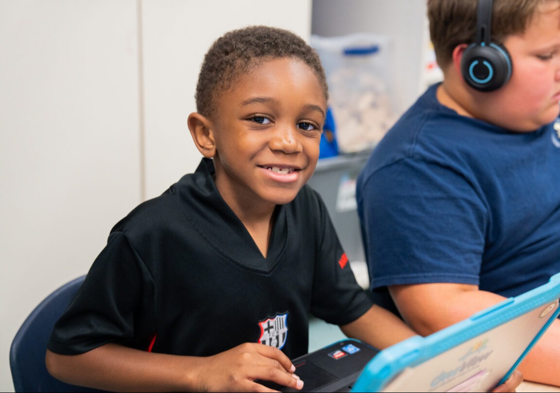 A student smiling and working on a class assignment