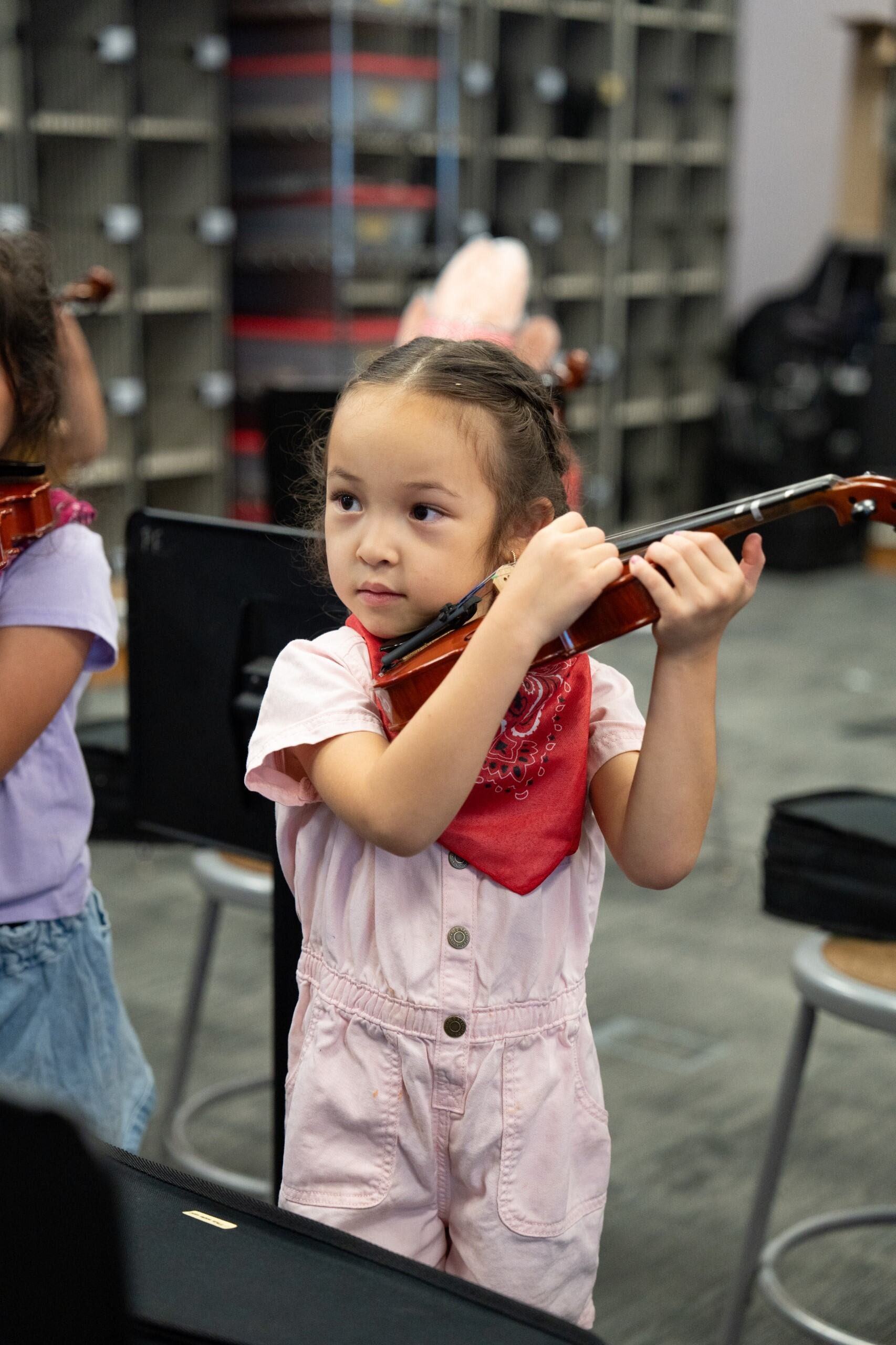 A student standing up and holding a violin, plucking the strings
