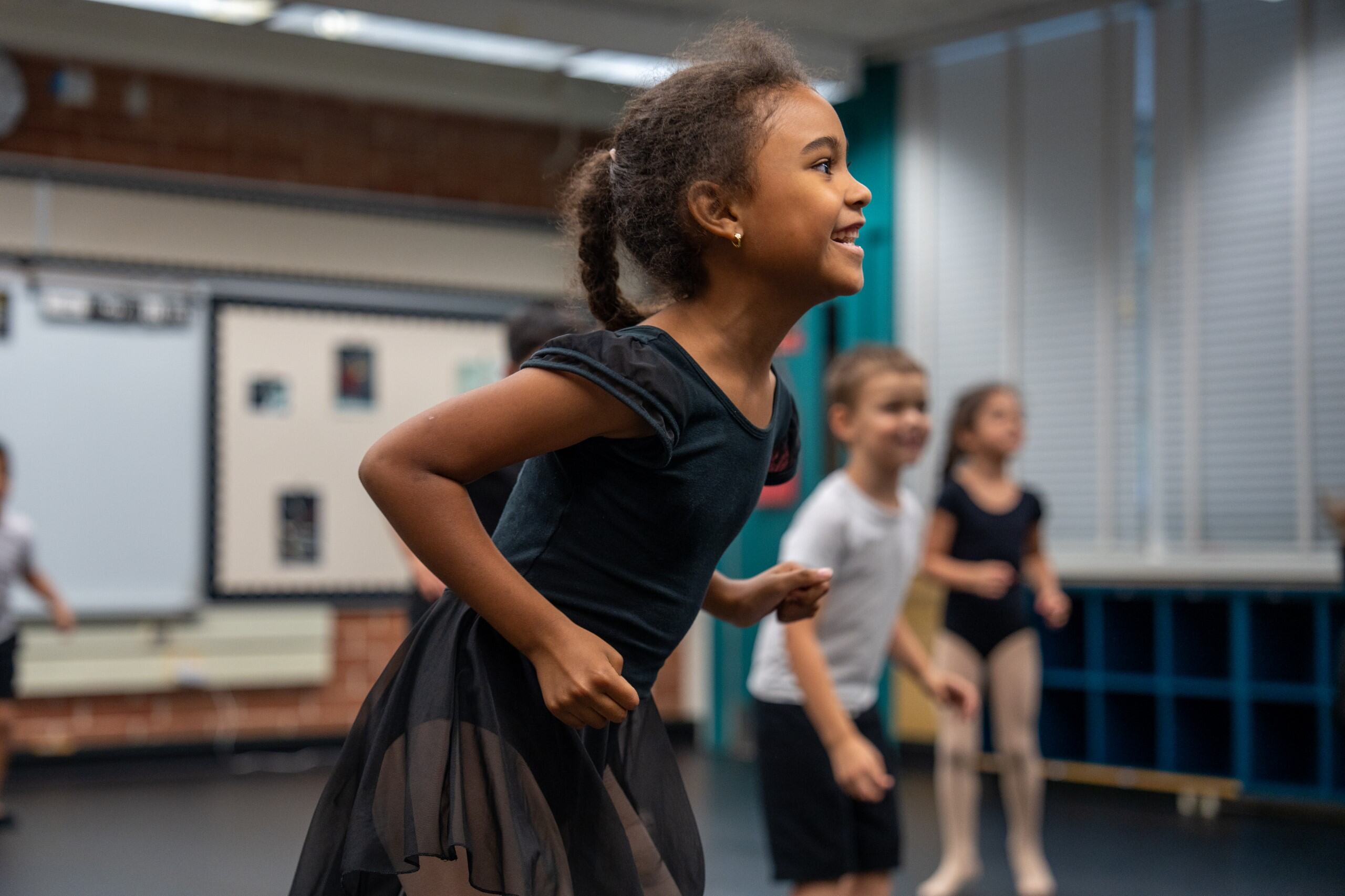 student in dance class smiling and learning forward 