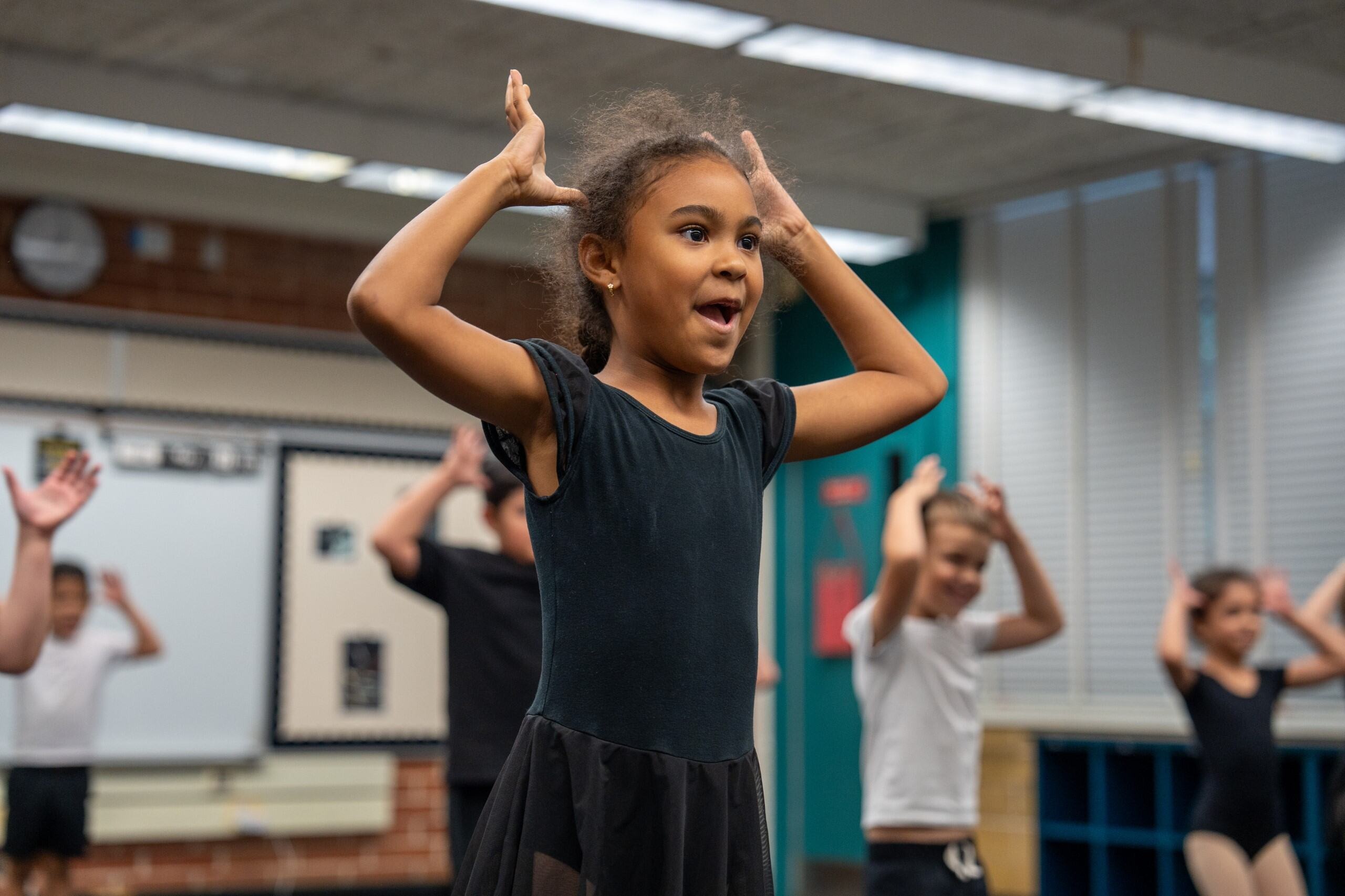 Student in dance class with her hands up by her head