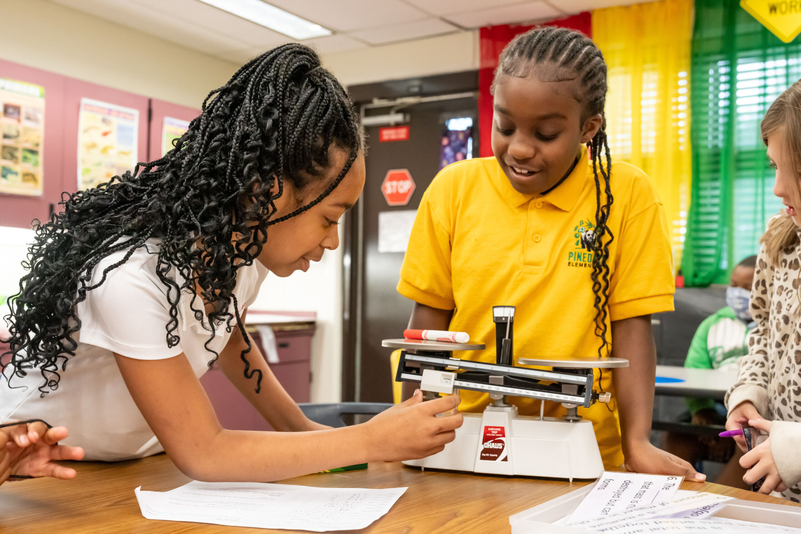 Two students measuring a marketer using a scale