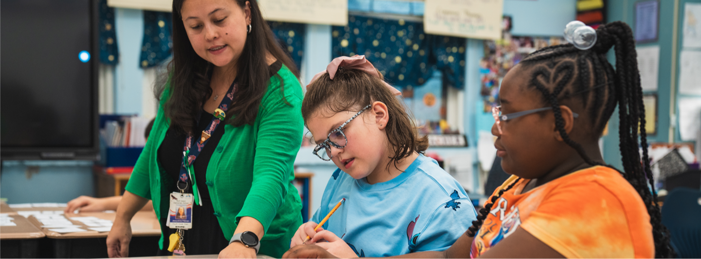 student at desk of students helping