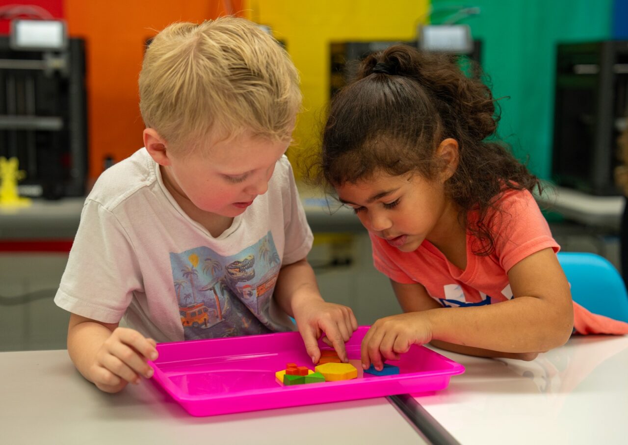 Two students using shapes to make an animal