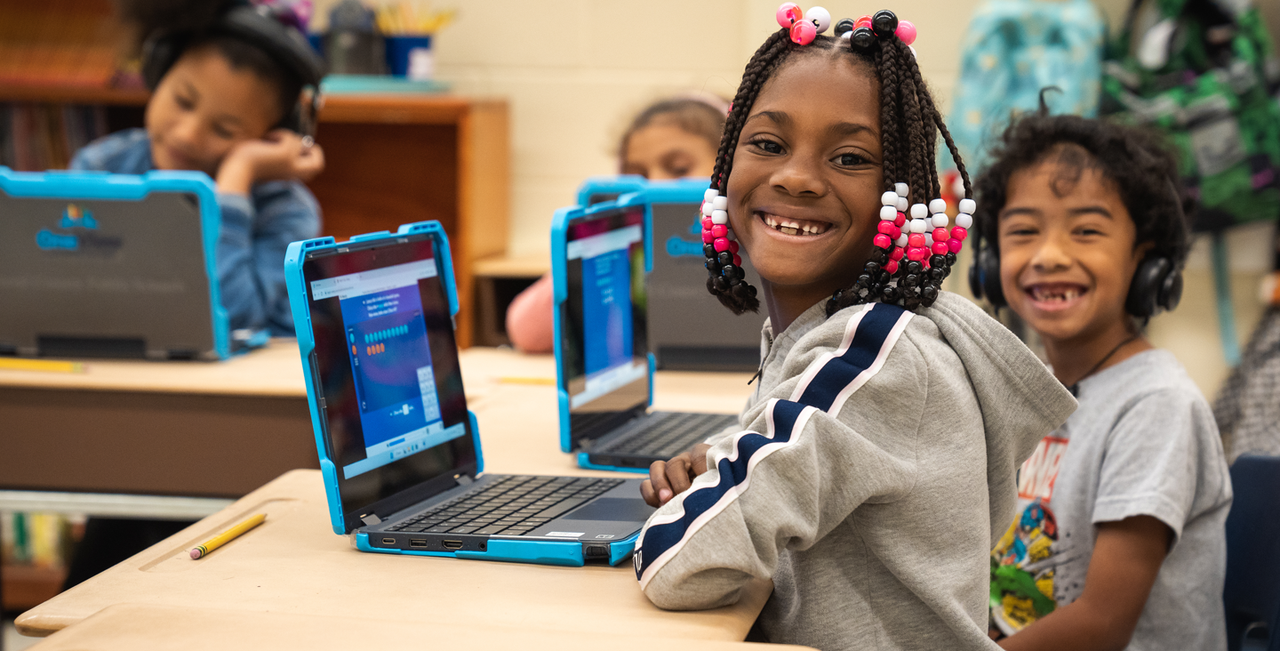 children smiling and working on their laptop