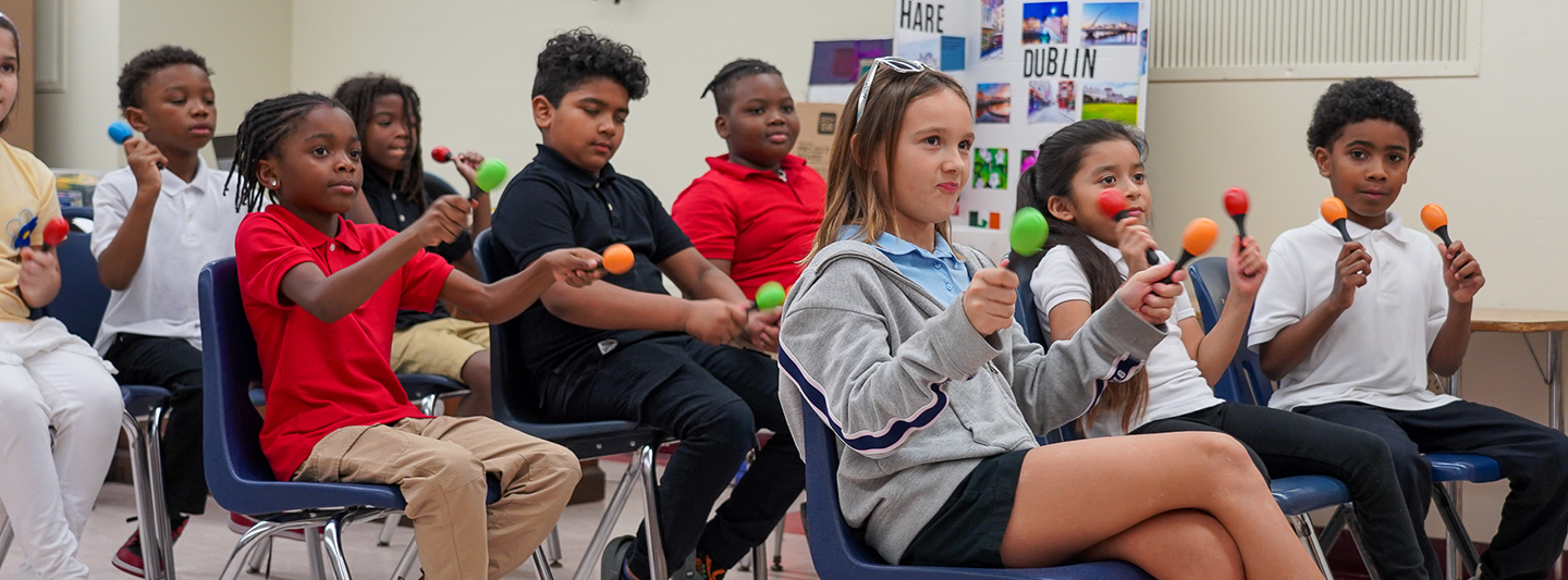 students shaking maracas while seated in class