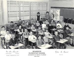 A group of people in a classroom, seated behind desks.