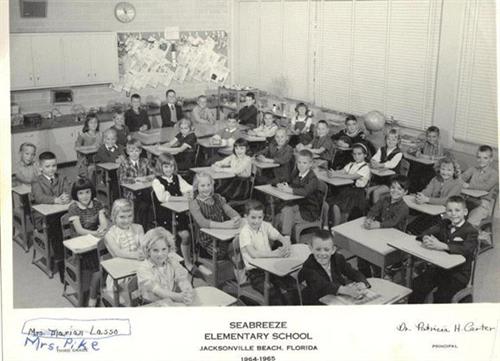 A group of people in a classroom, seated behind desks.