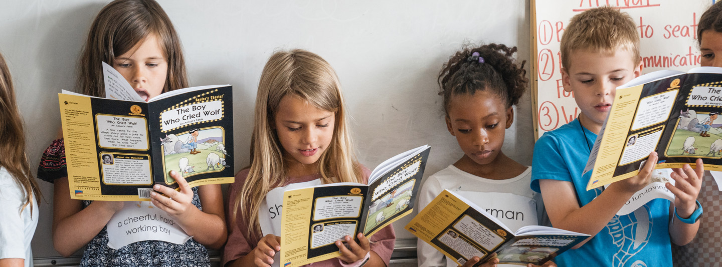 four students reading a picture book of the boy who cried wolf