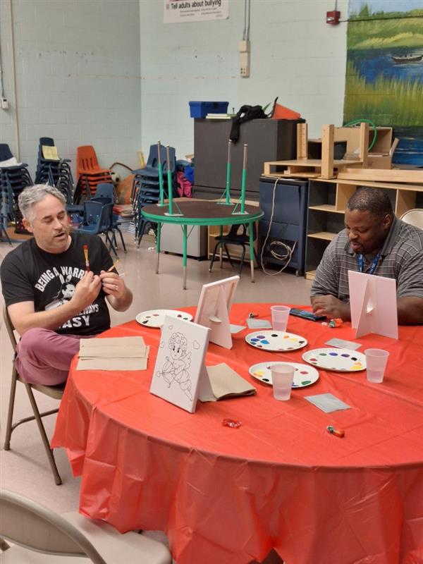 Two men enjoying an arts and crafts activity in a classroom setting.