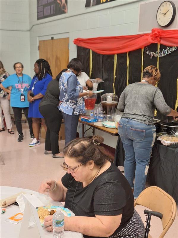 A bustling scene at a school event, with people serving food and enjoying the party.