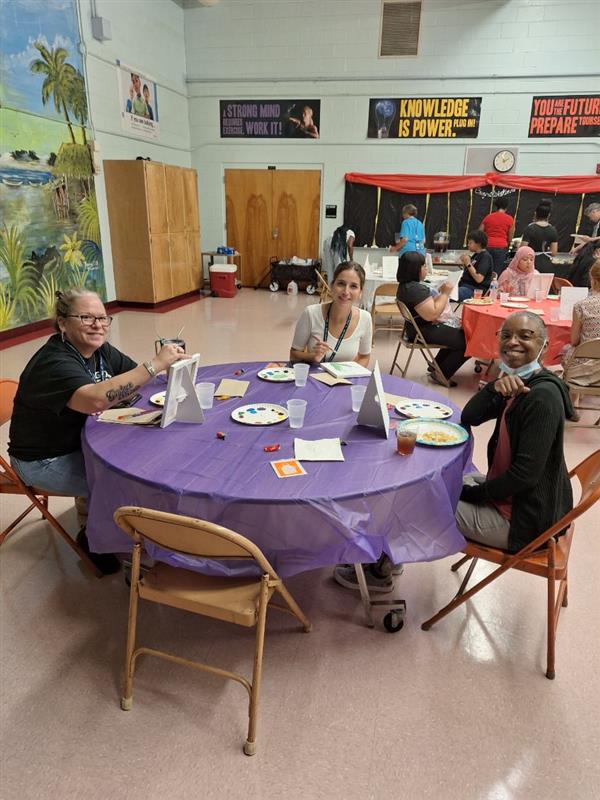 A bustling scene at a school event, with people serving food and enjoying the party.