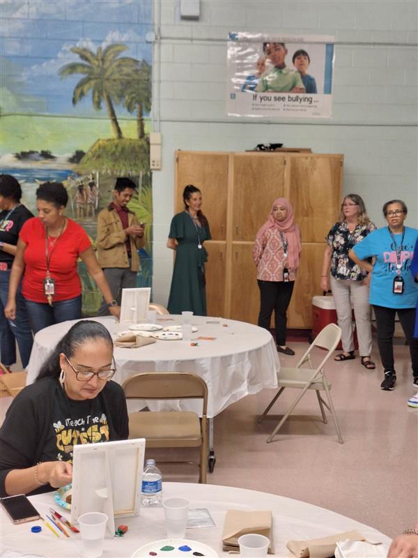 Group of people in a classroom setting, engaging in a craft or educational activity.