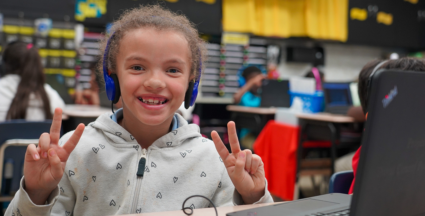 girl posing for a picture holding peace sign up with her fingers