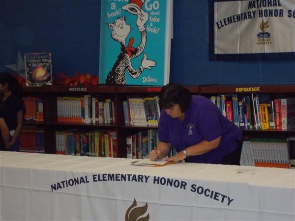 Woman signing a table at an event.