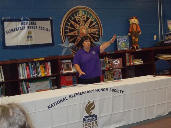 A person is standing at a podium in front of a table with an event banner.