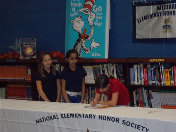 A group of students signing a pledge at an elementary school event.