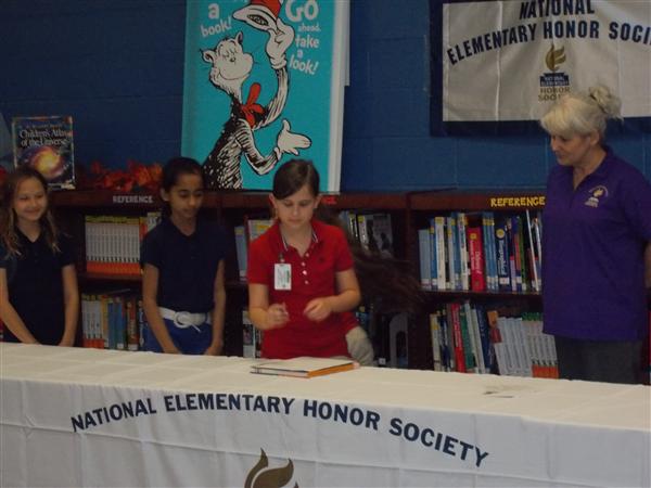 Young girl in front of a table at an event, signing papers.
