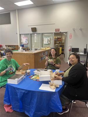 Three people enjoying food at a table.