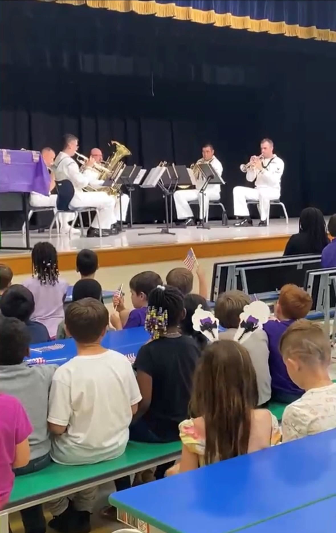 Military band performing in school auditorium.