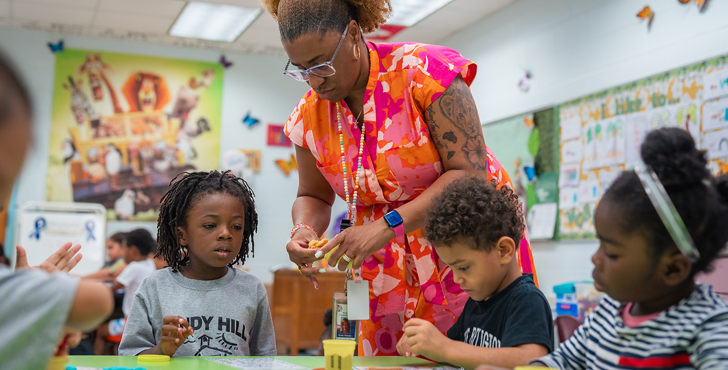 teacher helping students with a craft