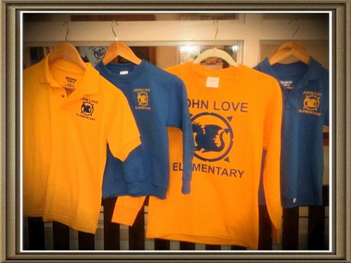 A collection of uniform shirts, some with text, hanging up in a room.