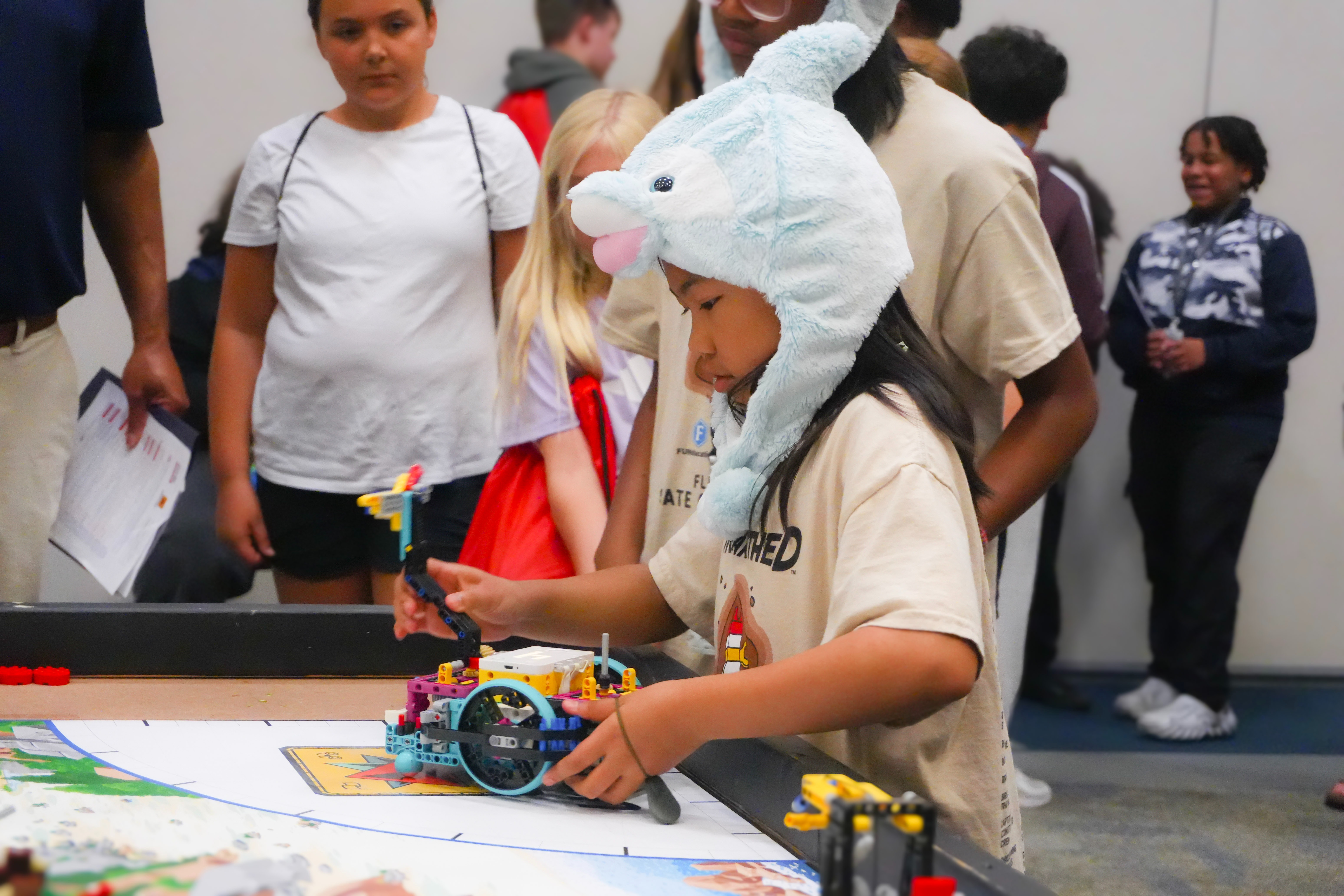 Student wearing a dolphin hat working with a robotic lego creation