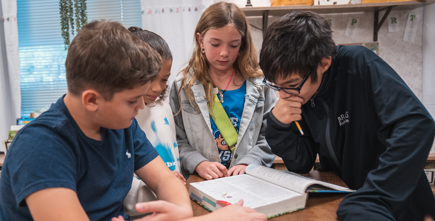 group of students looking something up in their textbook together