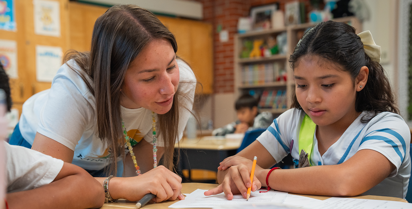 teacher helping a student with a worksheet