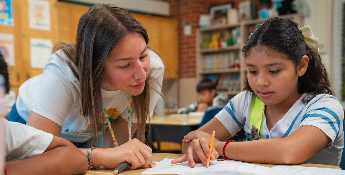 teacher watching student work at desk