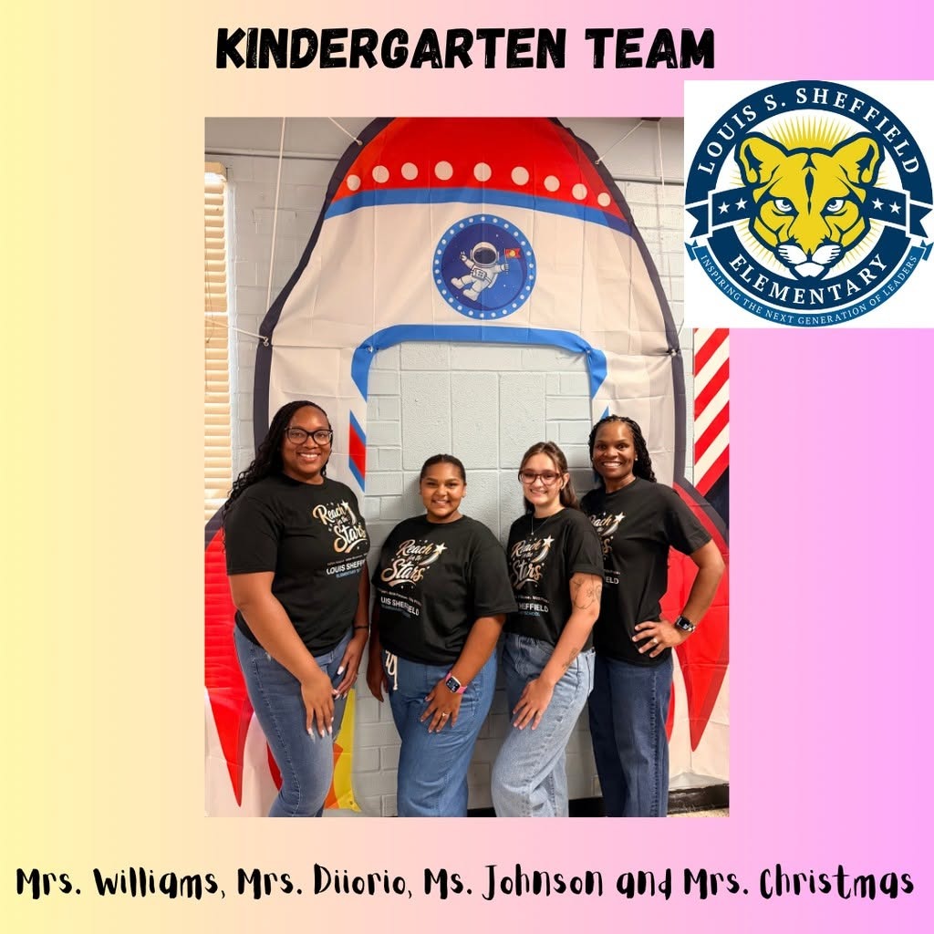 Four women stand in front of a backdrop of a rocket ship. They are wearing matching shirts and appear to be smiling.