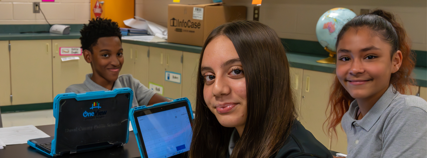 students at a table working on school laptops