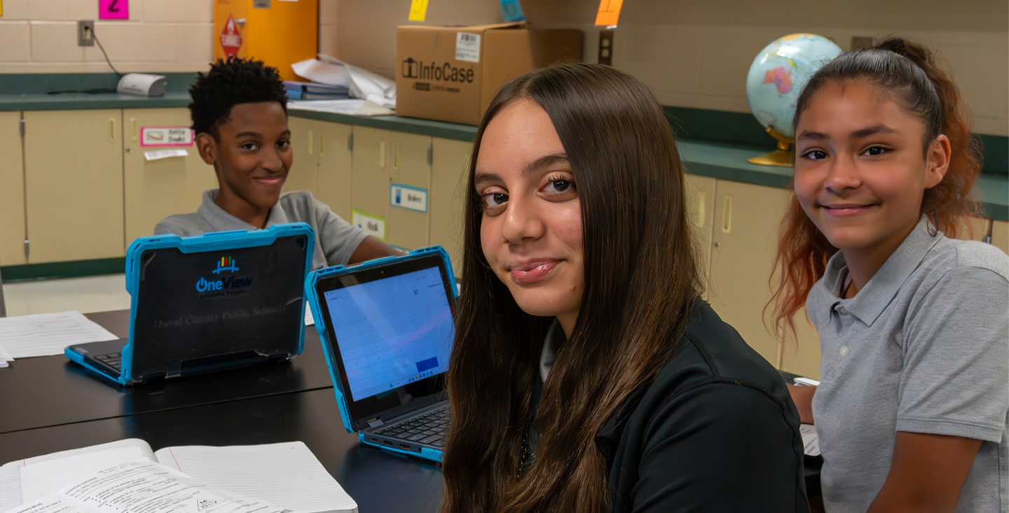 students at a table working on school laptops