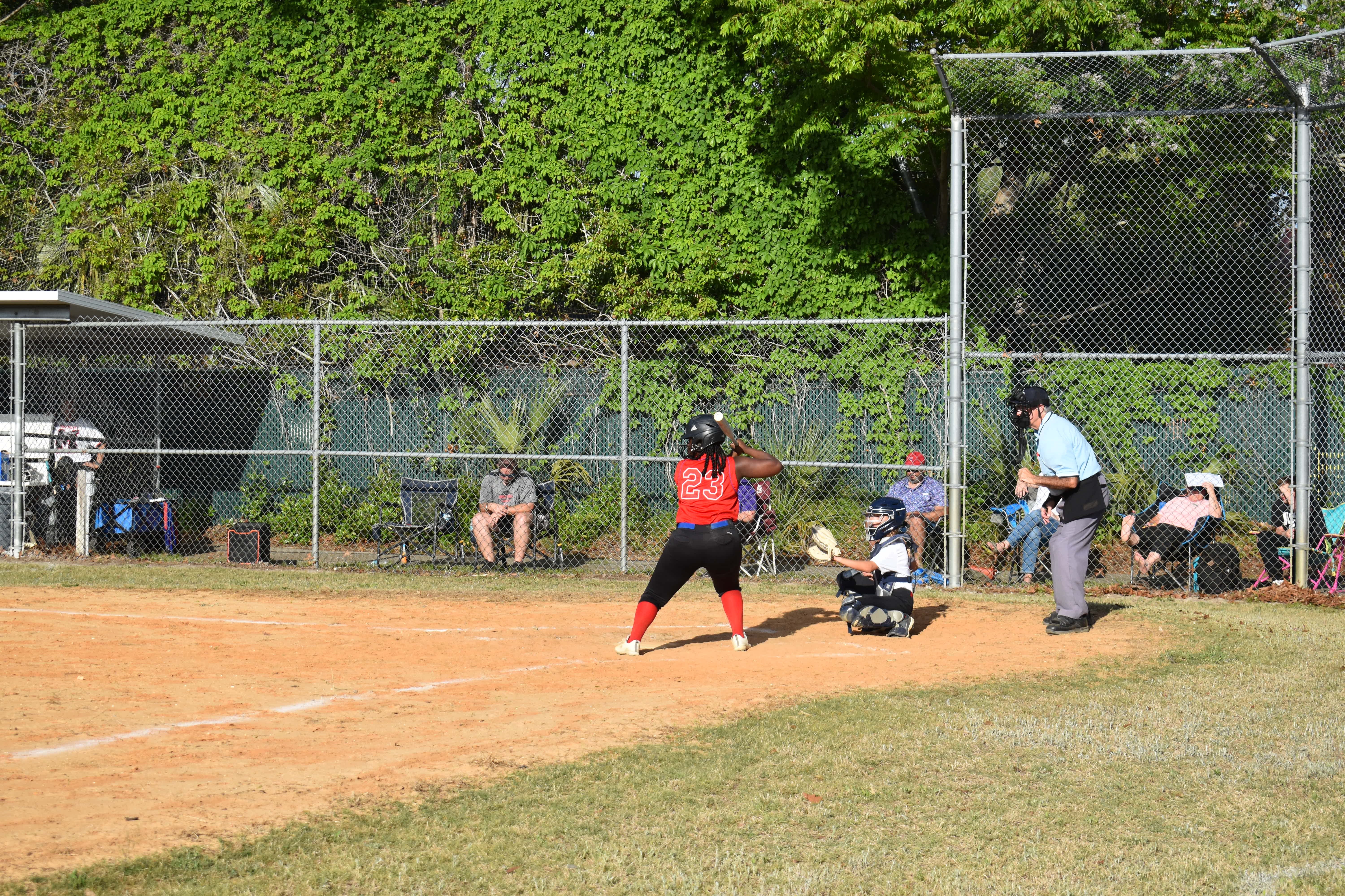 Softball player holding a bat at her right shoulder, waiting for a pitch.