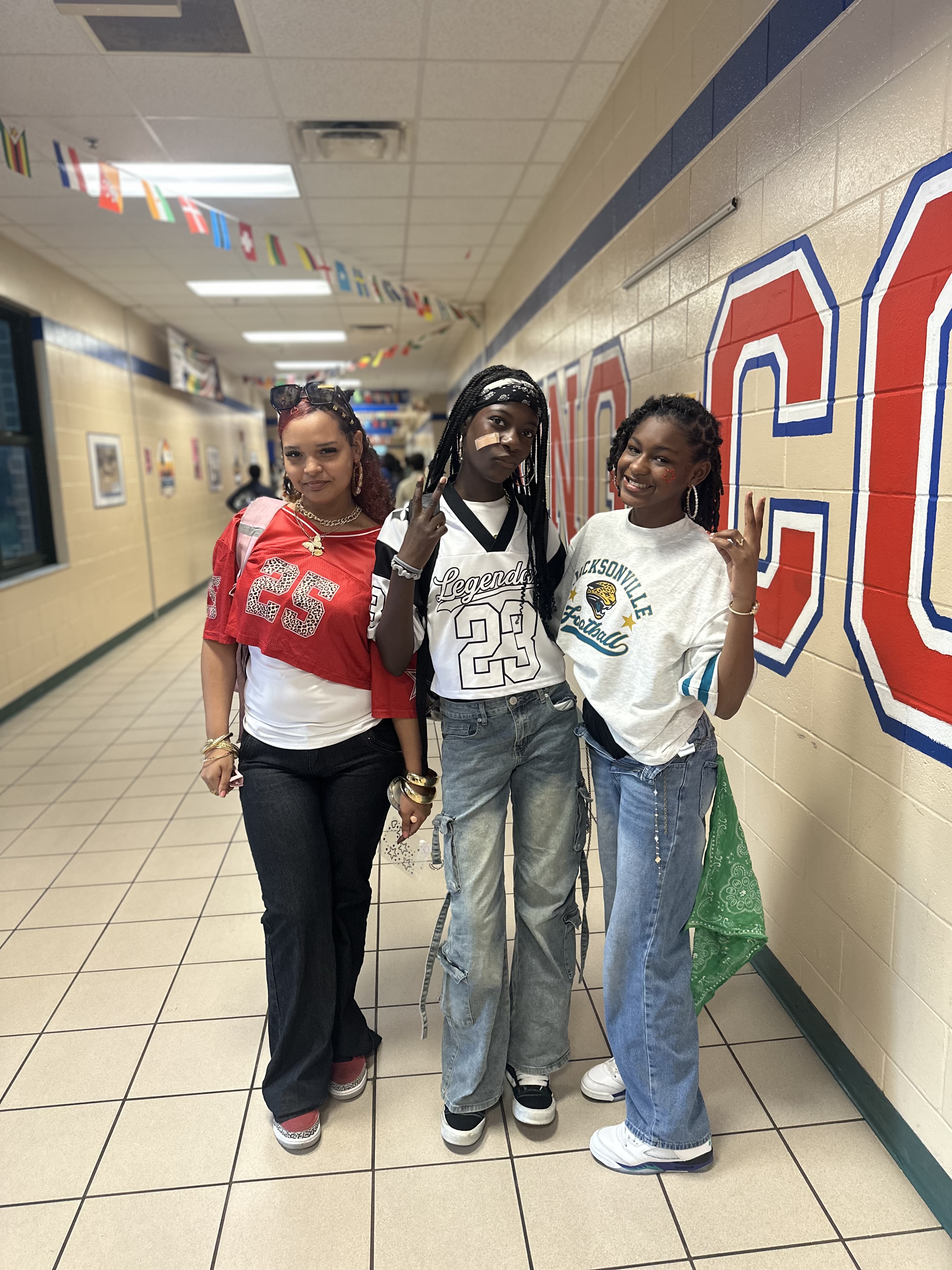 Three female students in the hallway for spirit day.