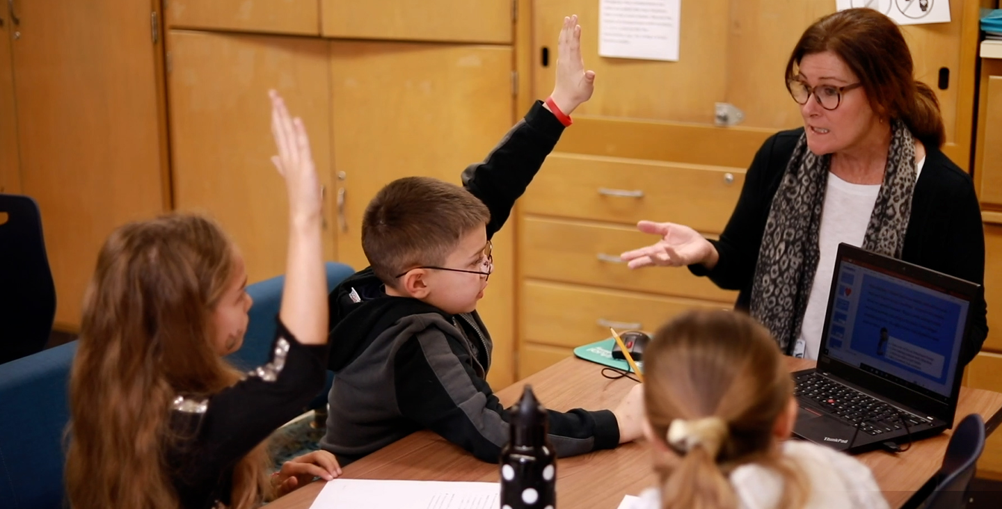 students in class raising their hands