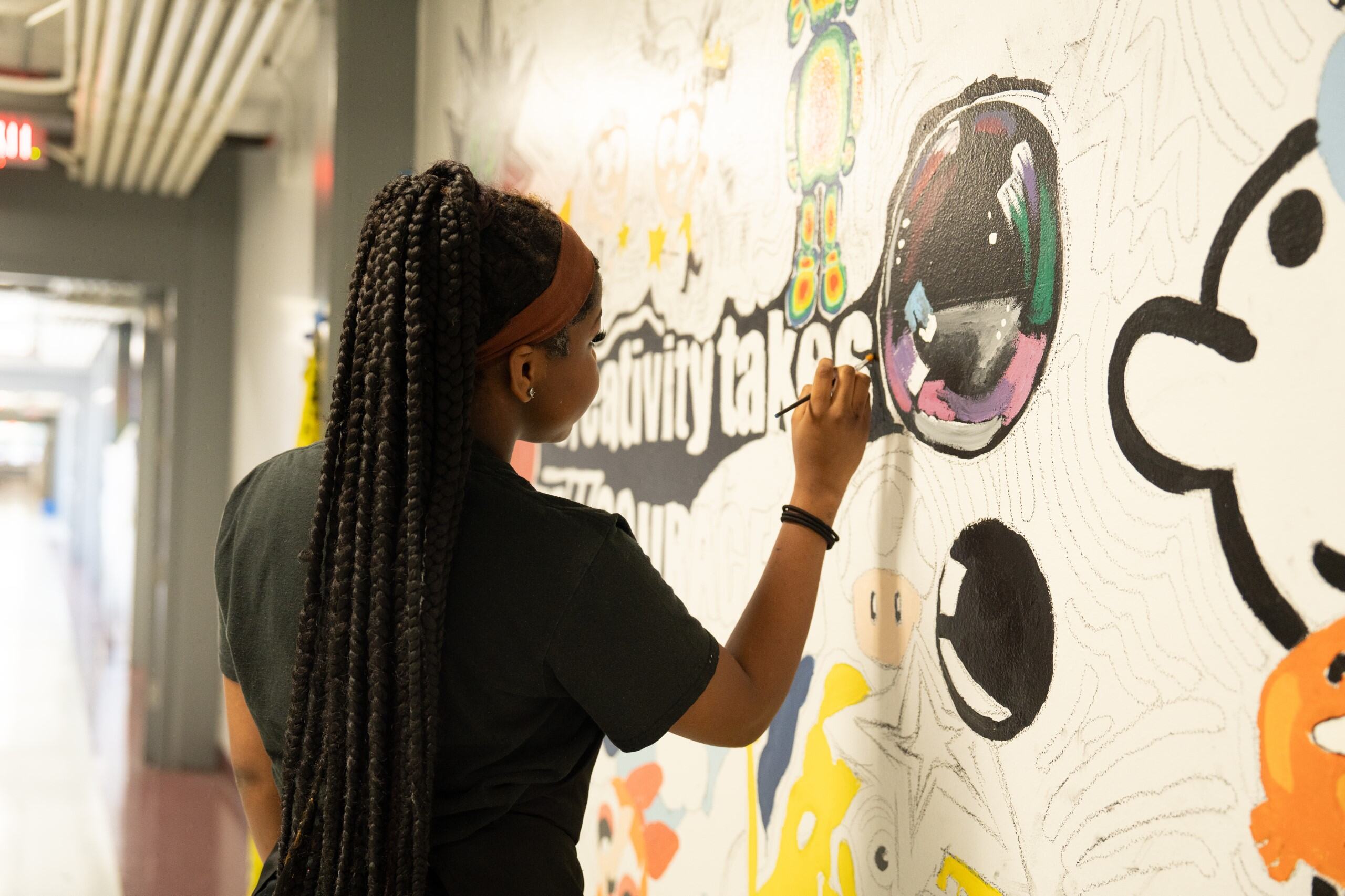 A student painting a mural on a wall