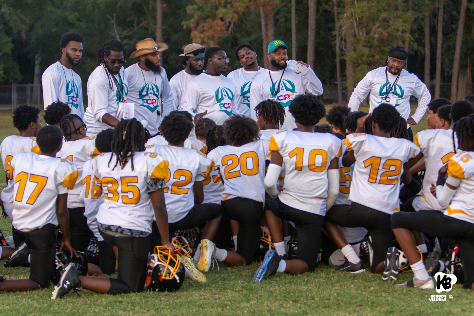 Football team huddled together taking a knee listening to their coaches